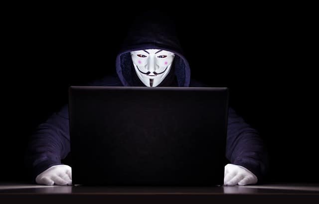 man met masker achter laptop