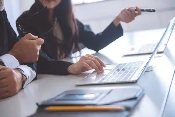 a man and woman sitting at a table with a laptop